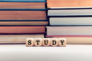 The word study on wooden cubes with stacked books background. Education, school and learning concept.