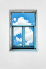 Window on a white concrete wall with blue sky and clouds view. Imagination, dreaming, freedom or inspiration concept.