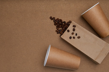 Two craft glasses with package and coffee beans on craft background . Monochrome photo - obrazy, fototapety, plakaty