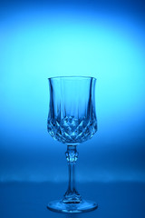 Wineglass on the light background. Fine cristal glassware concept. Vertical, toned in blue