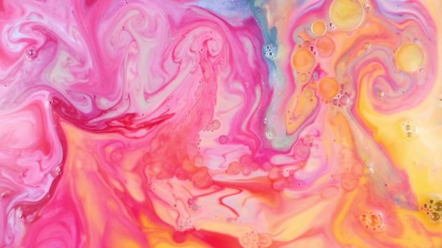 Close-up view of infusion of yellow paint in pink-blue paint in white milk. Vivid color mixing of multi-colored spots. Pink-yellow texture. Abstract art mixing paints in solution on white background.