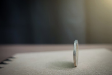 coins always have 2 side idiom idea concept, a Thai coin rolling on table with blurred background sunshine strong ligthing