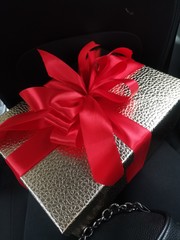 Golden gift box with a red bow on a black background