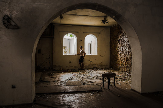 Young malet staring outside a windown in an abandoned building