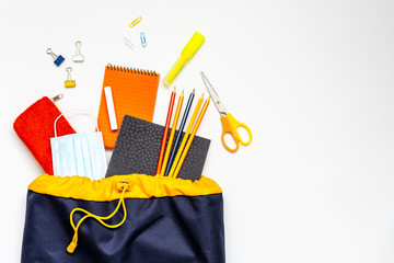 Schulartikeln verstreut und eine blaue Schultasche auf einem weißen Hintergrund. Schulbeginn, Flat...