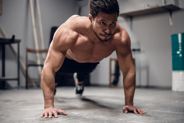 a muscular sportsman does push-UPS from the floor in the gym.
