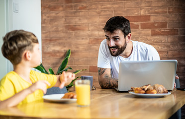 Fototapeta na wymiar Father and son talk and joke during breakfast