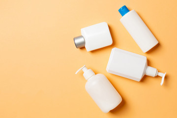 Set of White Cosmetic containers isolated on colored background, top view with copy space. Group of plastic bodycare bottle containers with empty space for you design
