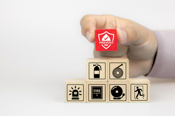 Fototapeta Close-up hand choose fire prevent icon on cube wooden toy blocks stacked with fire prevention icon for safety emergency concepts. obraz