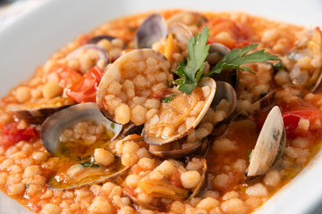 Piatto di fregola, una tipica pasta della cucina sarda, con vongole e pomodoro, cucina Italiana
