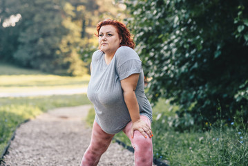 Obese woman doing leg warm-up exercises on a sunny day, weight loss training