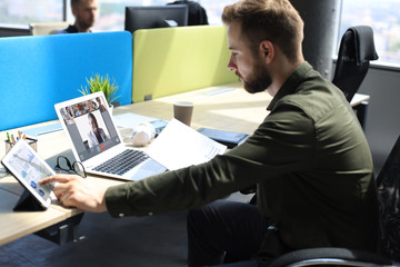 Businessman talking to his colleagues in video conference. Business team working from office using digital tablet, discussing financial report of their company.