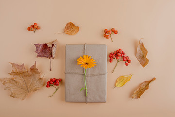 Autumn flat lay composition. Pretty gift box wrapped with craft paper and jute, decorated with flower on orange background. Thanksgiving day concept. Fall still life. Copy space. Selective focu s