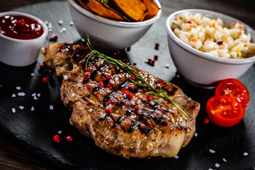 Grilled beef steak with baked sweet potatoes and vegetable salad on wooden table