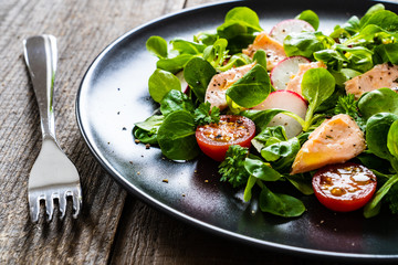 Salmon salad - roasted salmon and vegetables on wooden background

