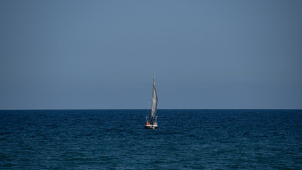 Fototapeta premium Small sailboat in the middle of the ocean