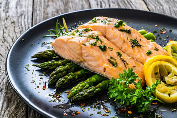 Roasted salmon steaks with  asparagus and lemon on wooden table
