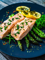 Roasted salmon steaks with  asparagus and lemon on wooden table
