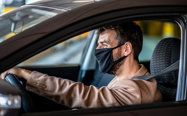A young man parks a car with a mask on his face, living during a pandemic caused by a virus