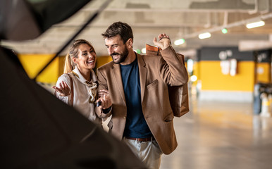 After shopping, the young couple packs things and bags in the trunk of the car
