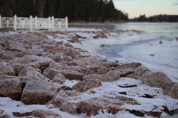 White bridge on a dam of crushed granite covered with ice and snow