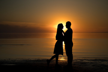 silhouette of a couple at sunset. Beautiful sunset of bright red orange color. Background for the travel website screensaver. Romantic picture, the concept of love.
