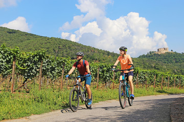 Junges Paar bei einer Fahrradtour in der Pfalz nähe Maikammer. Im Hintergrund Weinreben und das Hambacher Schloss (Model released)