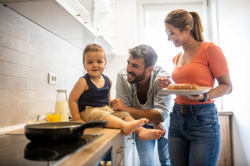 The family is making breakfast in their new kitchen, baking eggs in the morning, kid look at the camera