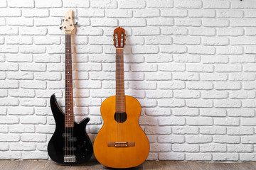 Fototapeta na wymiar Set of guitars on the floor against white brick wall