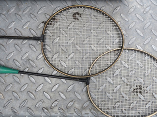 two badmintion rackets laying on a steel sheet