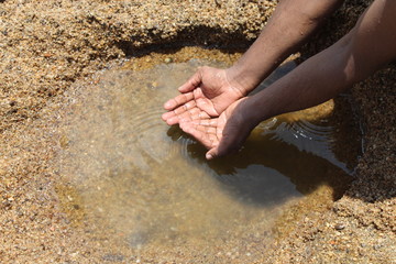 Man getting some water near the river to drink 