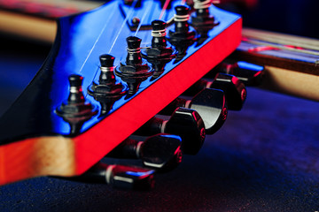 Guitar headstock with tuners on dark background