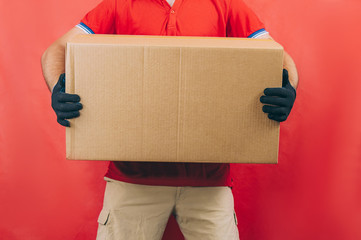 Guy with a cardboard box in his hands. Delivery service concept on red background.