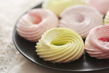 Fresh meringue rings on black plate