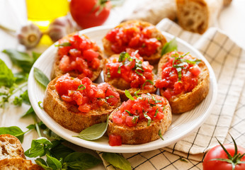 Tomato bruschetta a traditional Italian appetizer on a white plate.