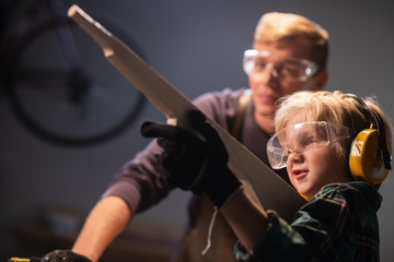 dad a carpenter carved a wooden gun for his son and the boy is happy with the gift.