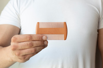 Male hand holding beard comb