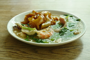 fried rice large noodles black soy sauce dressing mixed seafood and meat with Chinese kale in gravy sauce on plate