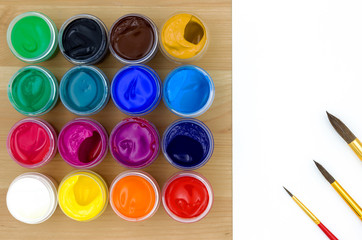 Gouache paints, brushes and white paper on a wooden table. Top view.  Back to school.  Creative...