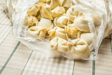 Handmade real dumplings are in plastic bag on table.