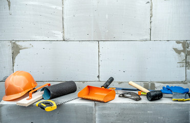 Set of construction tools on the background of a wall of aerated concrete blocks on a building site