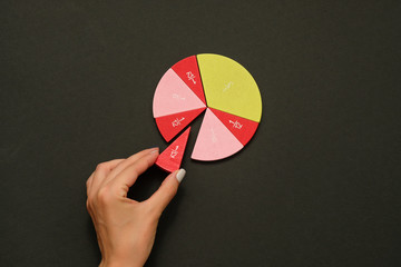 Colorful fraction circles arranged into a circle graph and hand, black background. - obrazy, fototapety, plakaty
