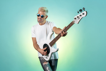 Handsome hipster man play white bass guitar in neon lights. Rock music concept. Rock star.