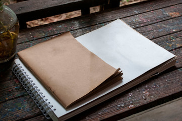 Notepad and drawing paper placed on an old wooden floor.