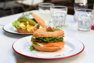 Salmon bagel on white plate. top view