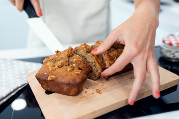 Young nutritionist hands cutting carrot cake into small pieces in the kitchen at home.