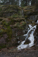 Fototapeta na wymiar Granite rock with a frozen white stream in cloudy weather