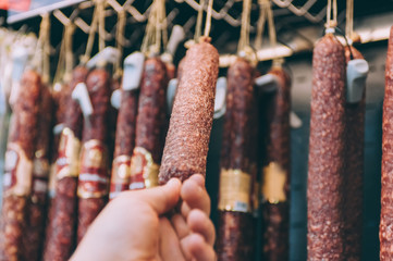 A guy in a supermarket picks a sausage in a shop window.