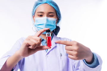 Hand of young woman doctor wear uniform white clothes and medical mask protection virus disease on nose while holding use finger pointing to test tube with blood sample over isolated white background.