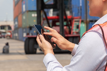 Shipping officer using smart phone  at the container yard.
